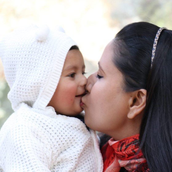 mother kissing infant